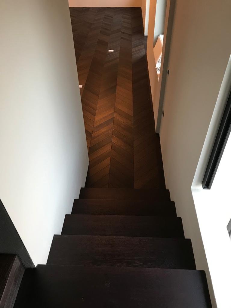Scala in rovere tinto scuro in continuità con il pavimento